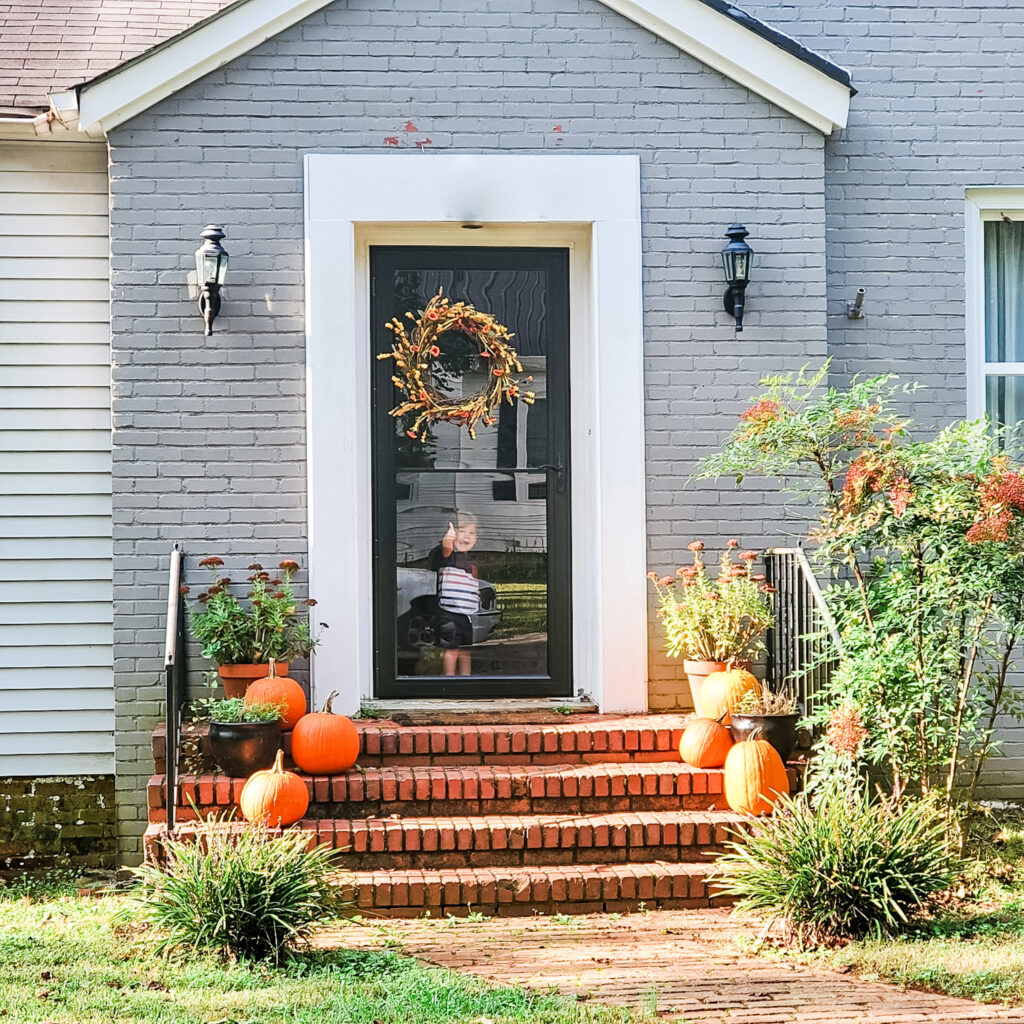 Fall pumpkins and wreath displayed on decorated home exterior. 